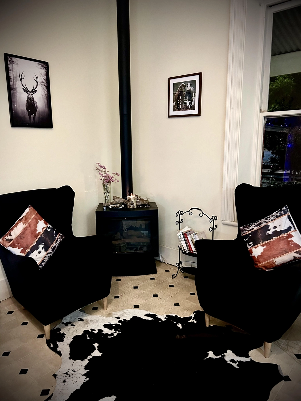 Cosy fireplace lounge with velvet armchairs and cowhide rug at Nature's Table Cafe