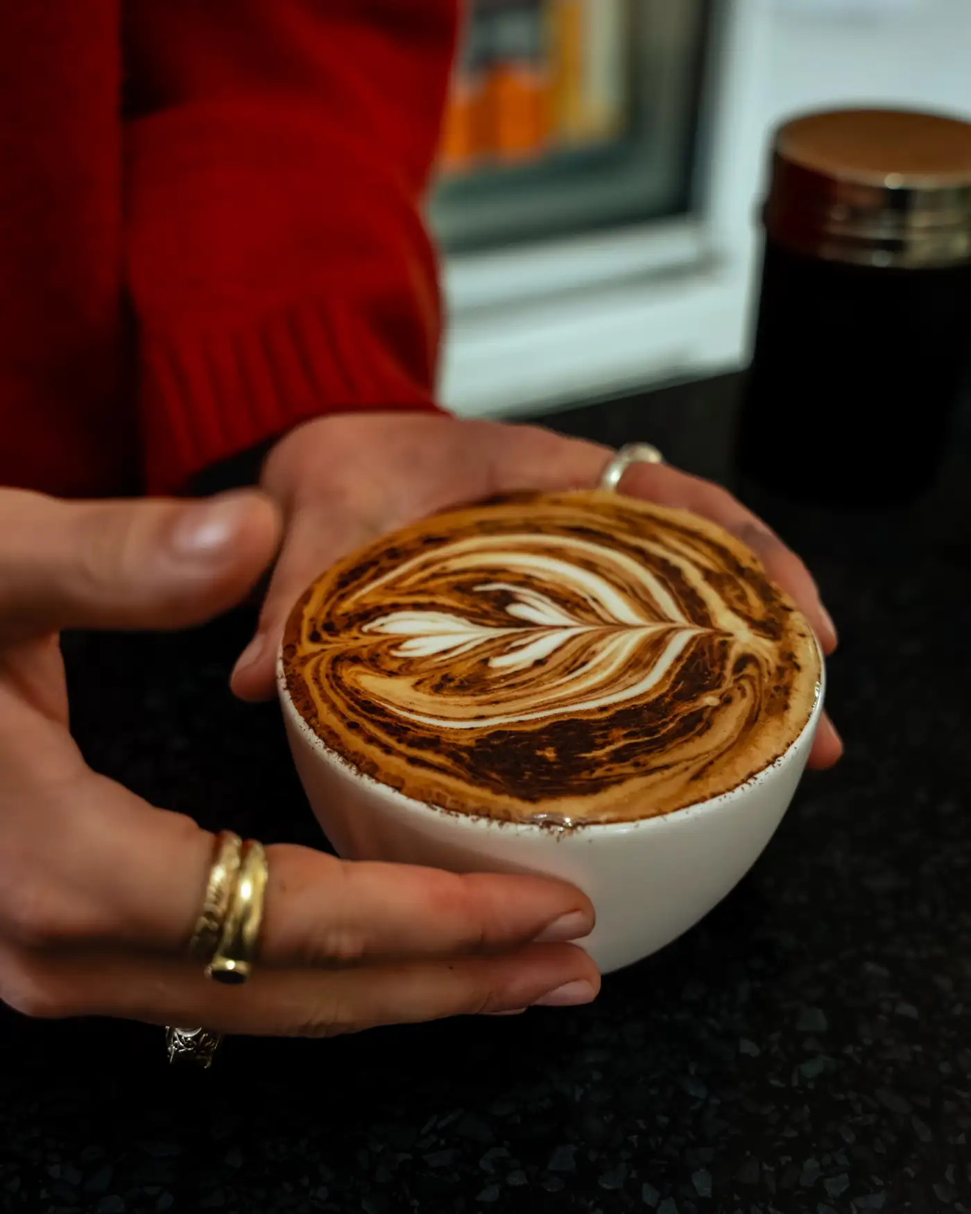 Handcrafted latte art coffee held in hands at Nature's Table Cafe