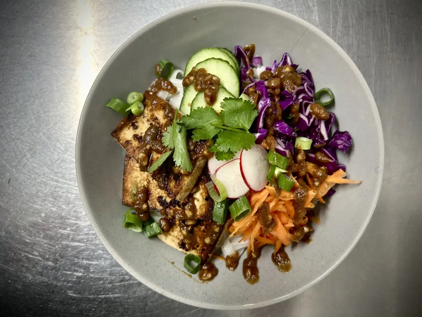 Colourful tofu noodle bowl with fresh vegetables and herbs